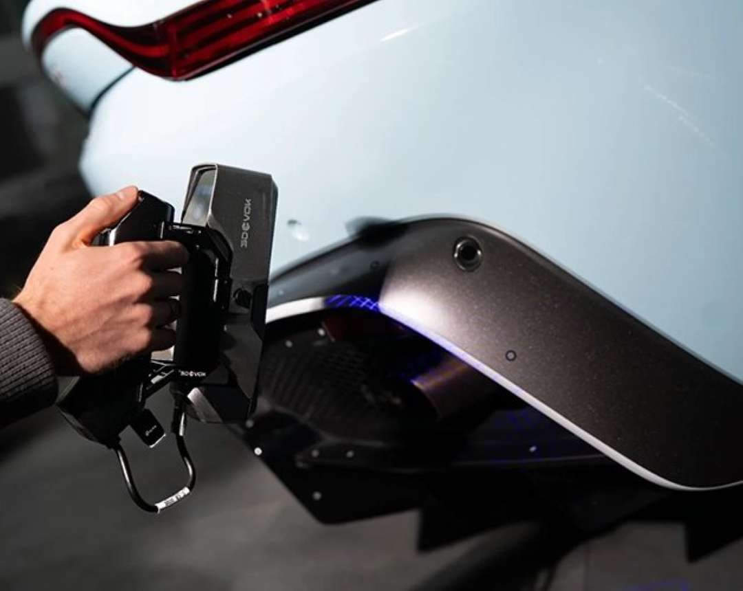 El escáner 3D de mano proyecta luz láser azul sobre la parte trasera de la carrocería de un automóvil