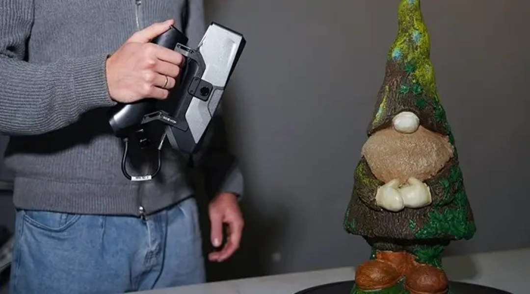 Escáner 3D de mano junto a una figura de gnomo pintada con textura detallada