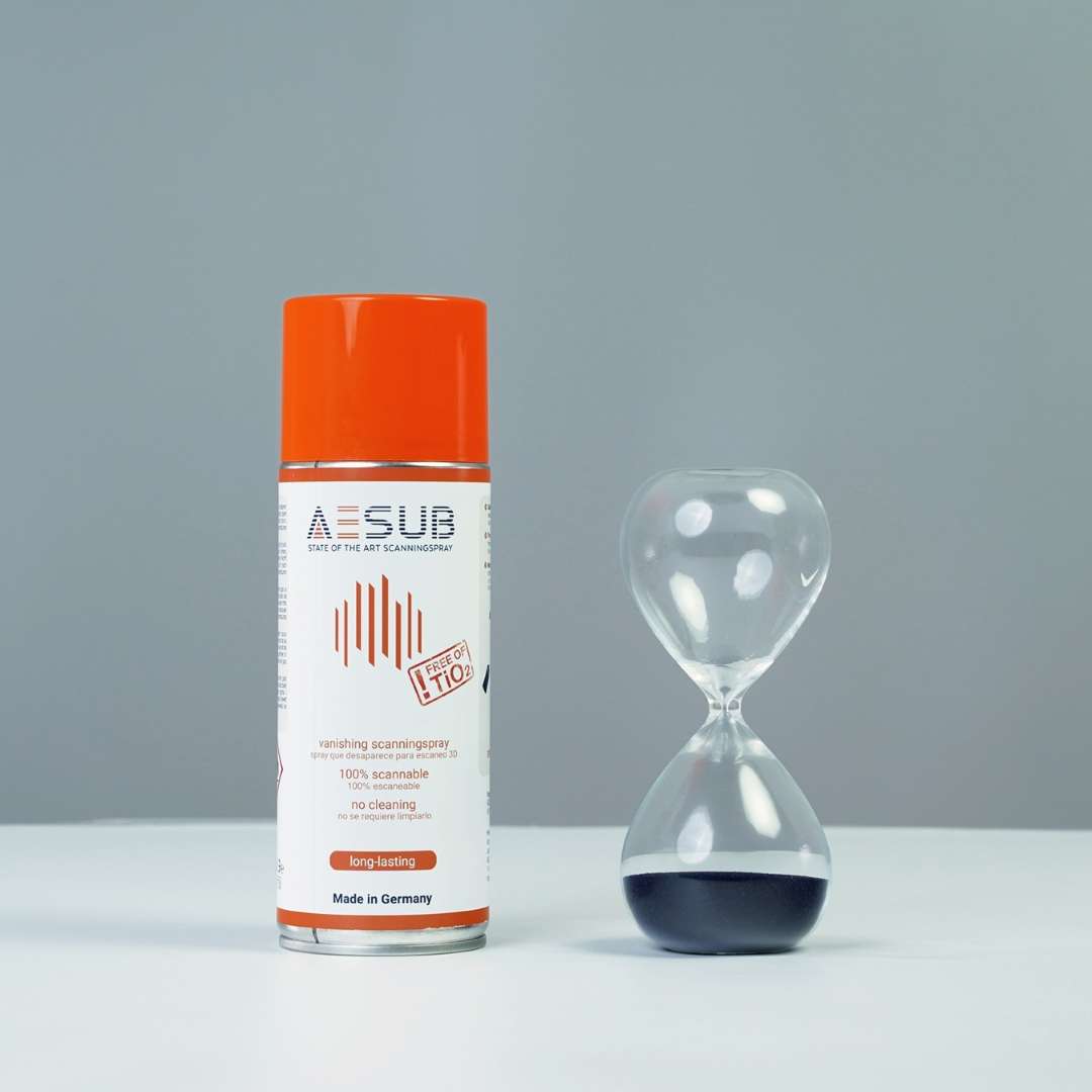 Bote de spray AESUB Orange 400 ml junto a un reloj de arena de vidrio con la arena en la parte superior, representando el largo tiempo activo antes de la sublimación