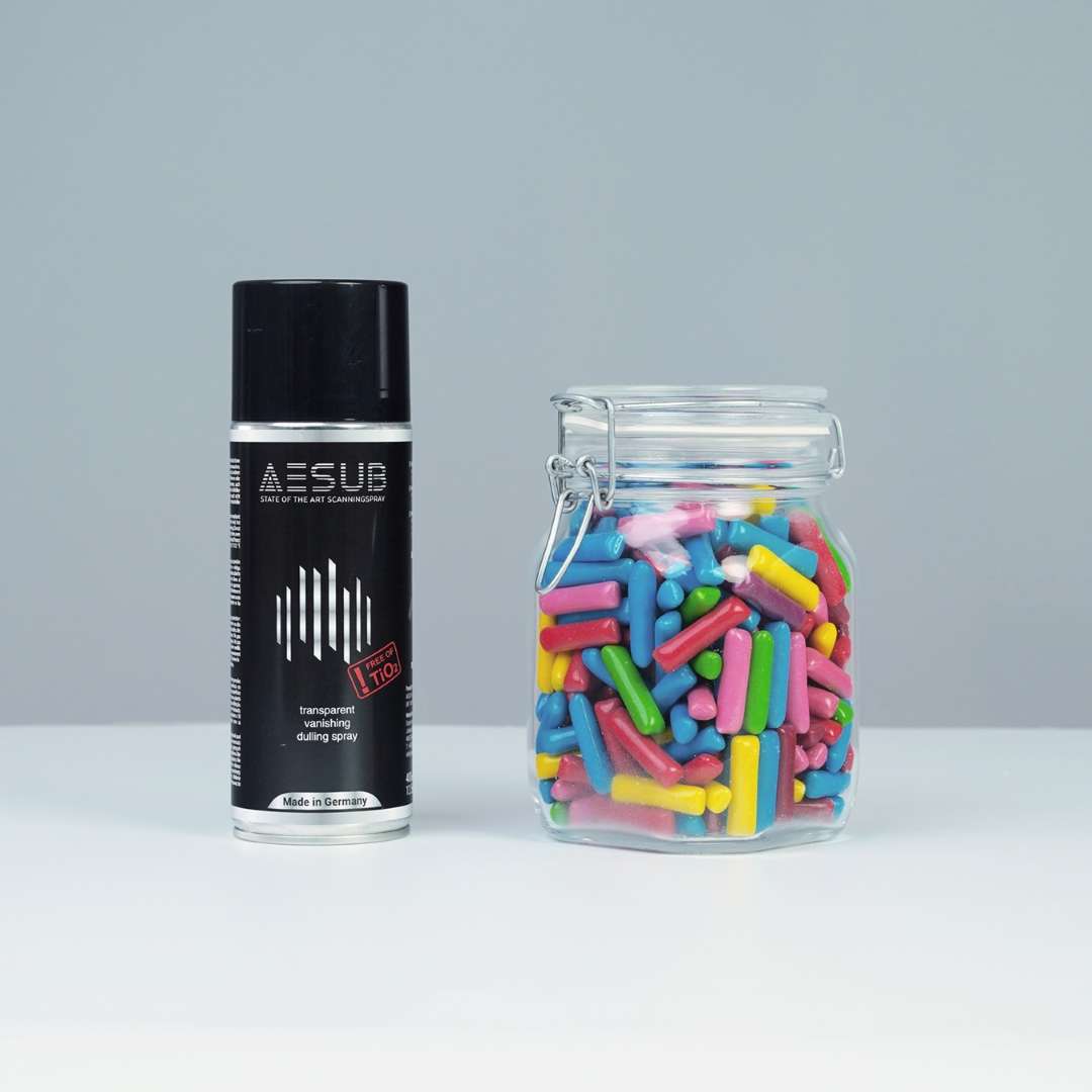 Bote de aerosol AESUB Transparent de 400 ml con etiqueta negra junto a un tarro de vidrio transparente con caramelos de colores — antes de la aplicación del spray
