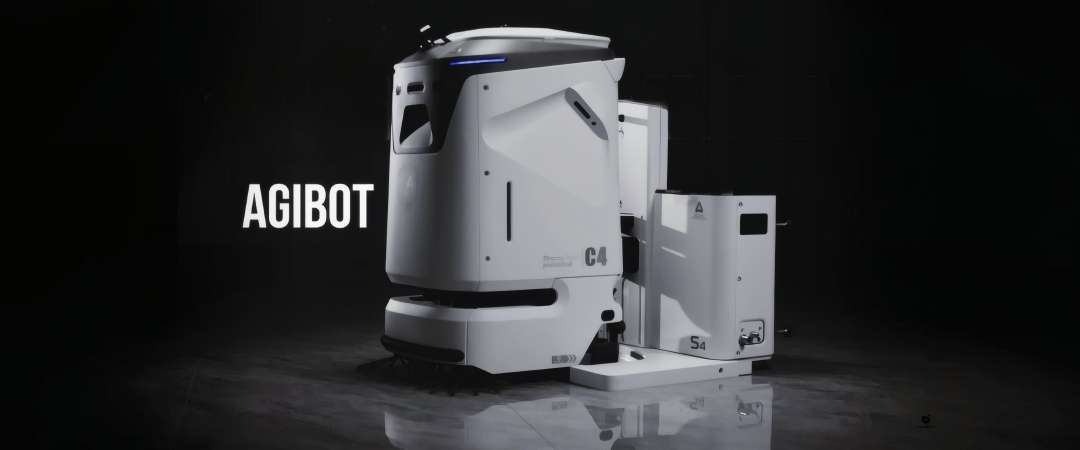 Robot fregasuelos AgiBot C4 en el muelle de la estación de carga, se aprecian el cepillo delantero y el indicador luminoso de estado