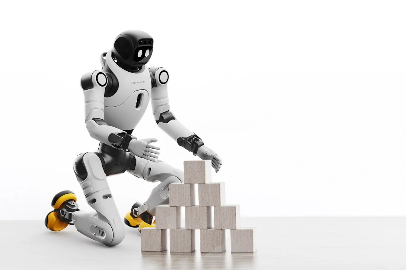 Robot humanoide blanco arrodillado junto a una mesa, colocando con cuidado una pirámide de cubos con ambas manos.
