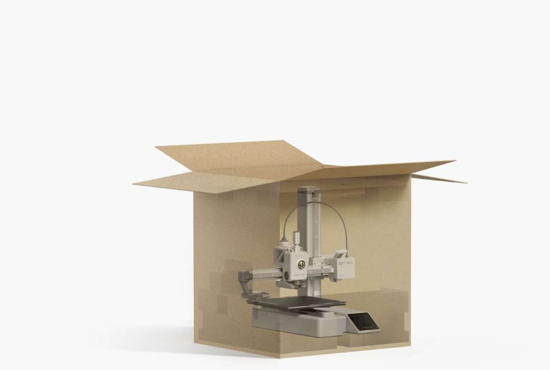 Caja de cartón con las solapas abiertas y paredes translúcidas, a través de las cuales se ve una impresora 3D con columna vertical, cabezal, plataforma y pantalla frontal.