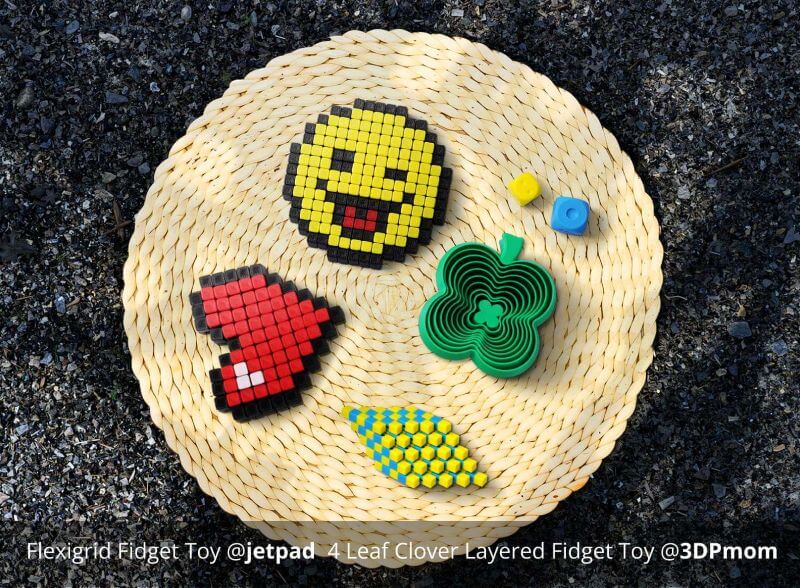 Piezas impresas con filamento Bambu PLA Basic - juguetes antiestrés coloridos impresos en 3D, que incluyen un emoji de píxeles y un corazón, sobre una alfombra tejida.