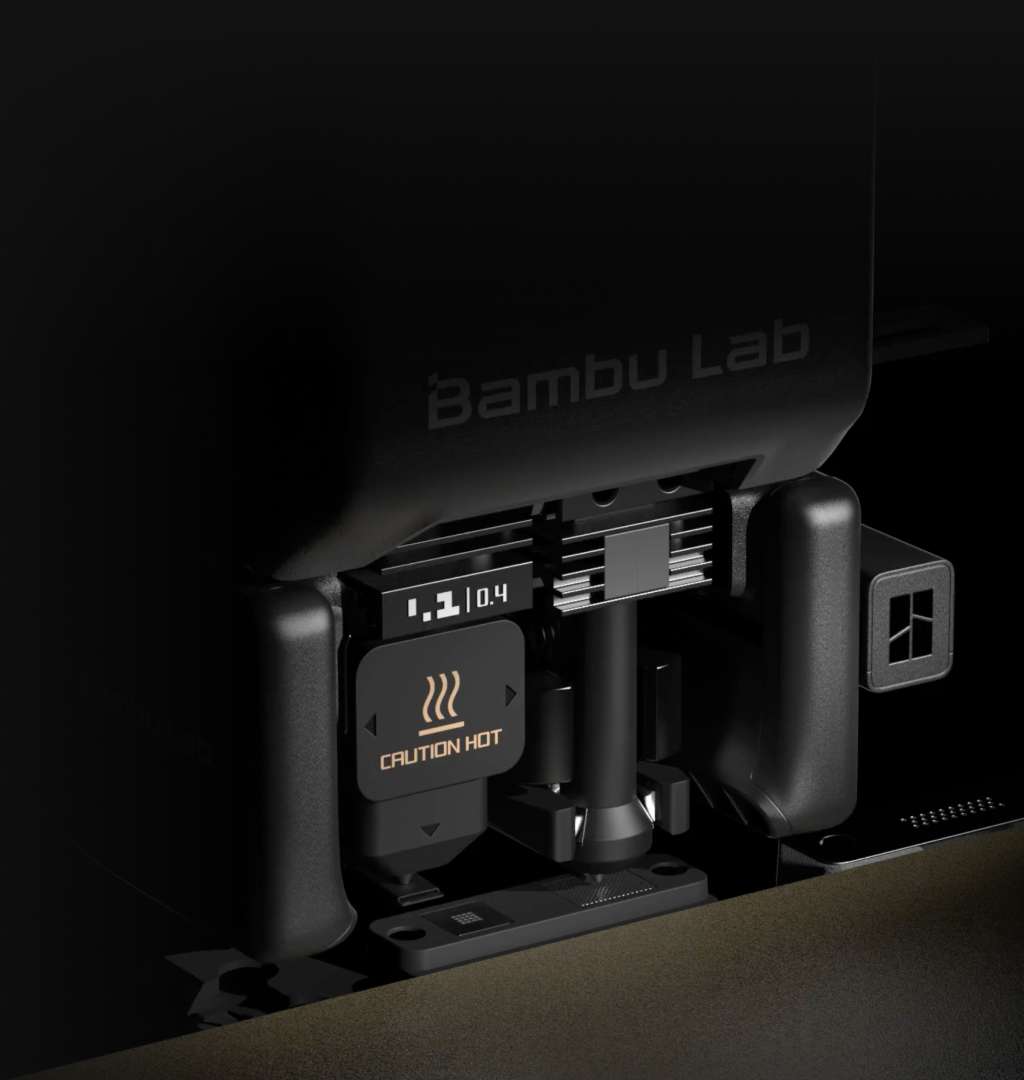 Primer plano de la boquilla doble de Bambu Lab H2C con marcado de 0,4 mm y una etiqueta de advertencia de superficie caliente