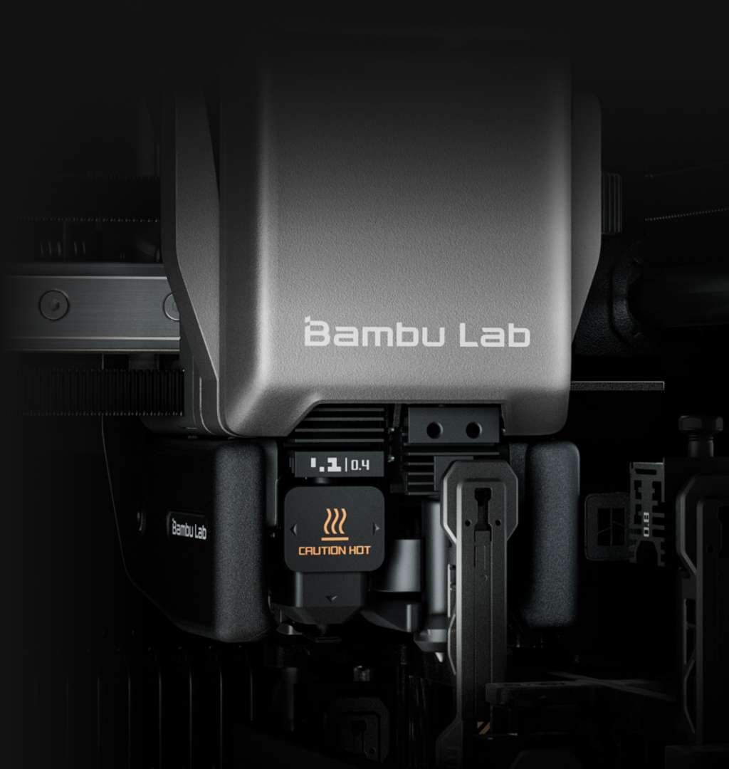 Primer plano de la boquilla doble de Bambu Lab H2C con marcado 0,4/0,4 mm y advertencia de superficie caliente del hotend