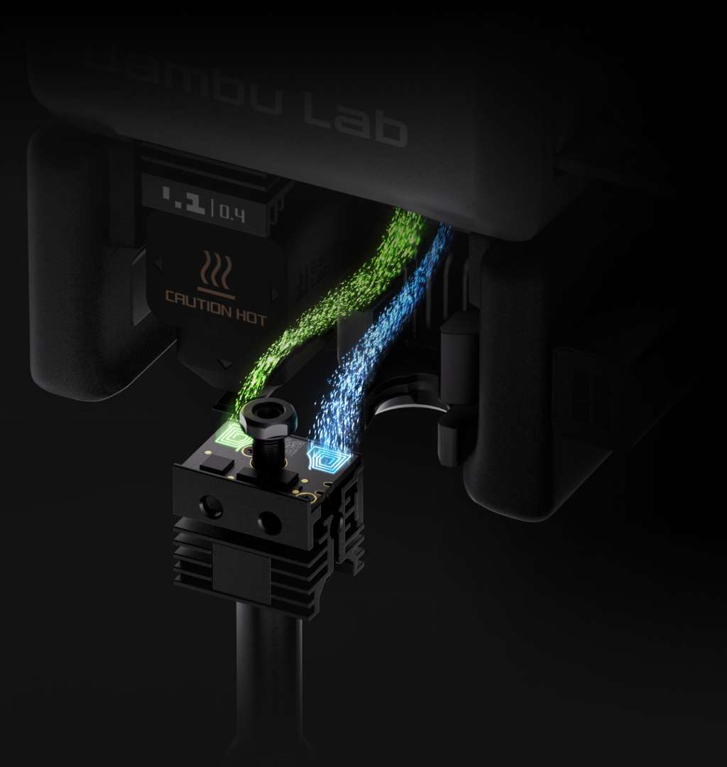 Primer plano del hotend Bambu Lab H2C con las vías de alimentación de filamento iluminadas en verde y azul y el disipador de refrigeración