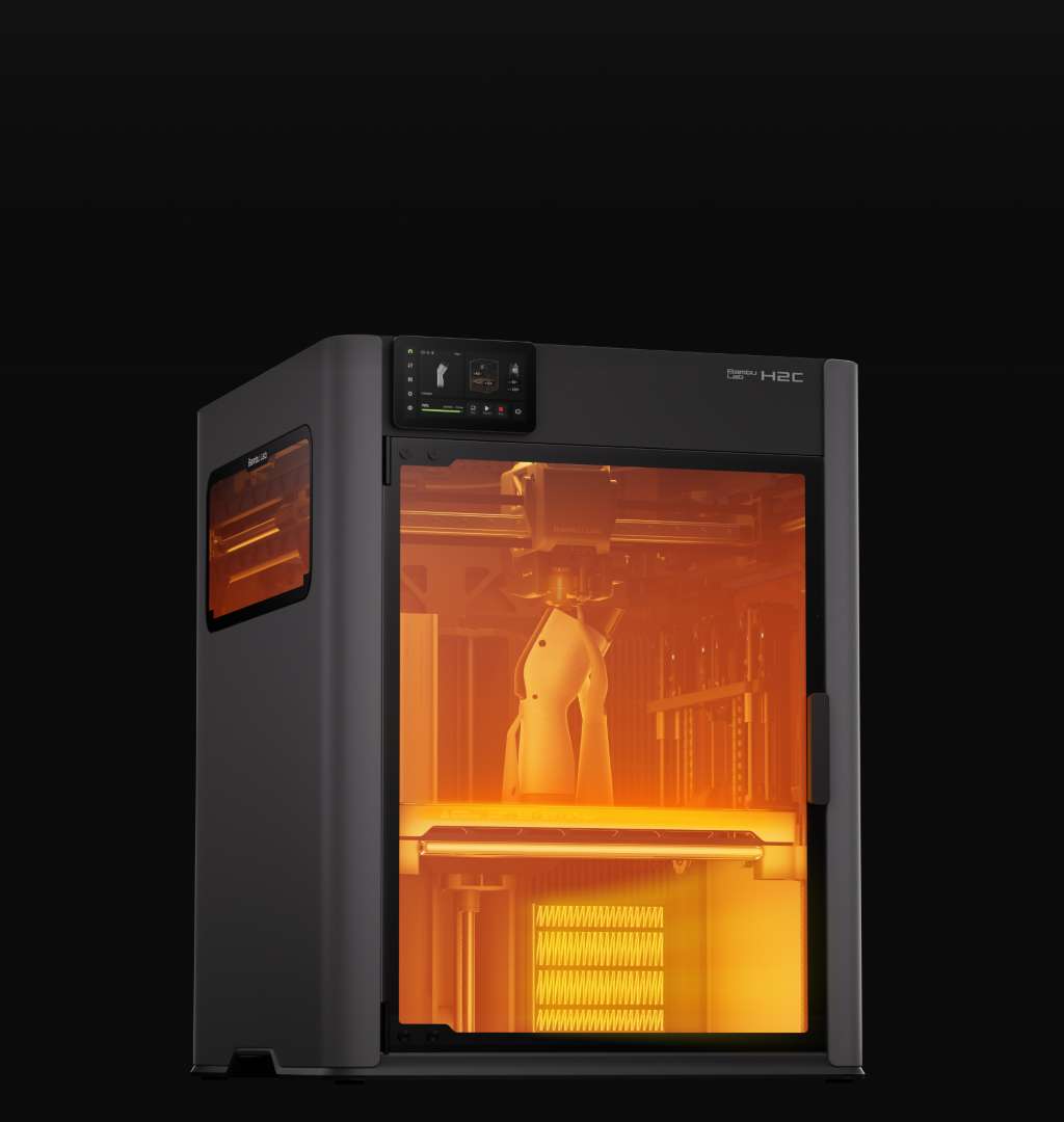 Impresora 3D cerrada Bambu Lab H2C con el interior iluminado, donde se ve la boquilla doble y la mesa de impresión