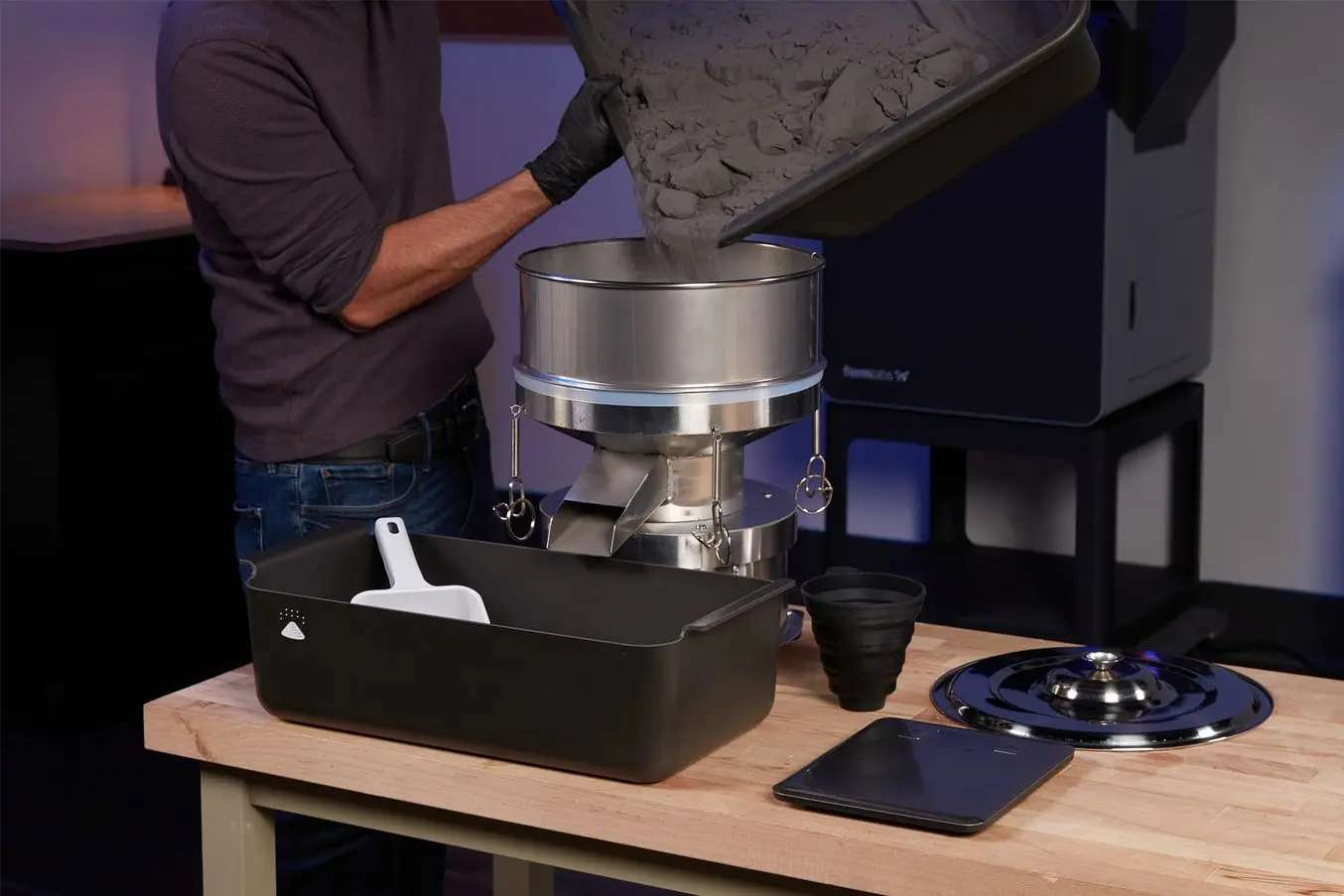 Operario utilizando el Formlabs Fuse Depowdering Kit para extraer y limpiar piezas impresas por SLS en un puesto de trabajo