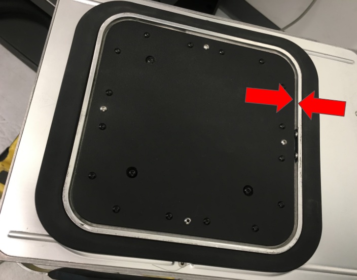 Flechas rojas señalando la ranura entre el borde de la plataforma y la pared interior de la cámara Fuse 1 — zona crítica de acumulación de polvo durante la limpieza de cambio de material