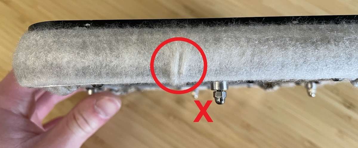 Primer plano del sello de fieltro de la cámara Fuse 1 con un desgarro visible señalado en círculo rojo y una marca X — indica que el sello debe sustituirse, no limpiarse