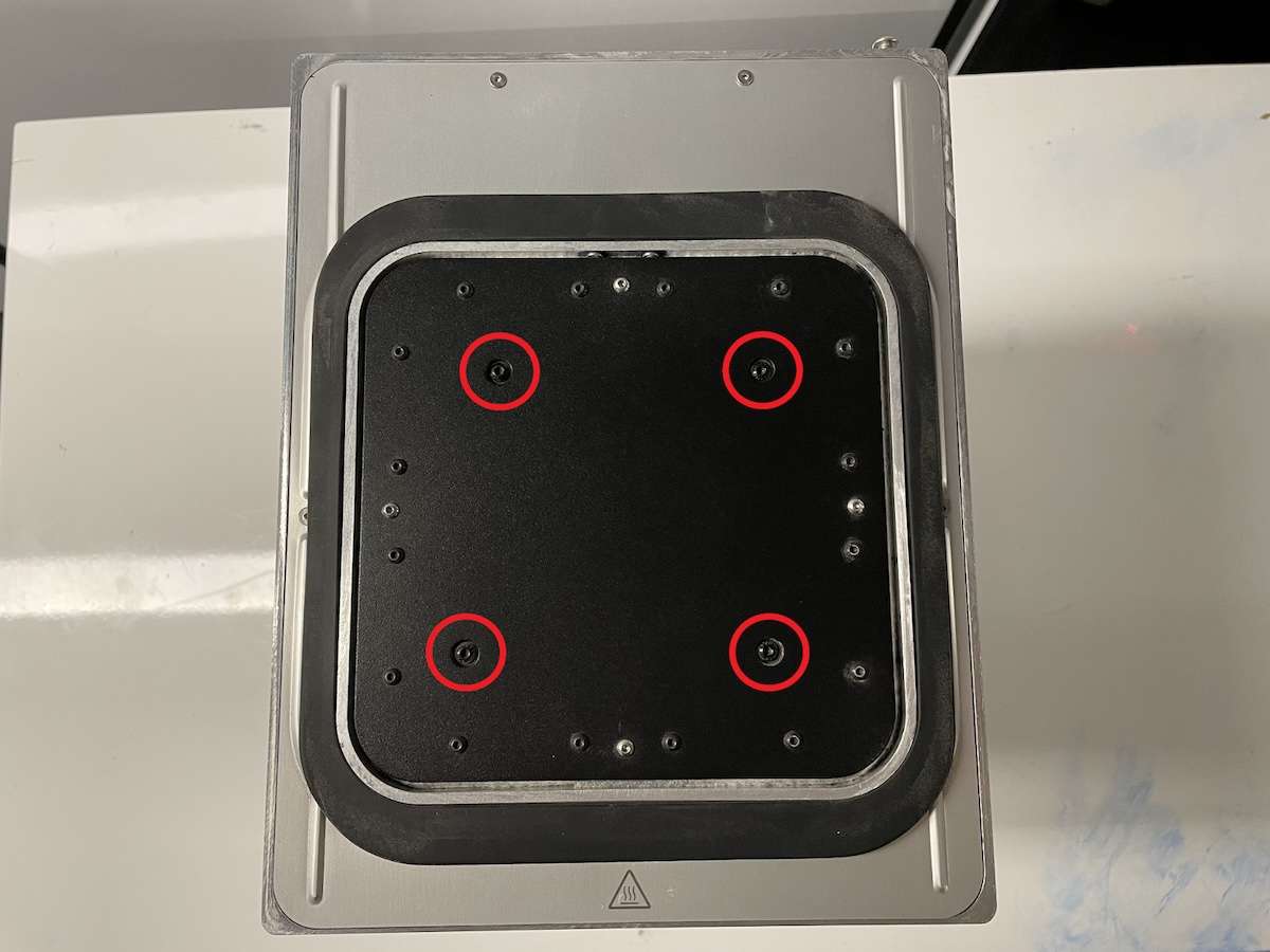 Vista superior de la plataforma de impresión de la cámara de fabricación Fuse 1 con las cuatro posiciones de tornillos M4 de cabeza redondeada señaladas en círculos rojos