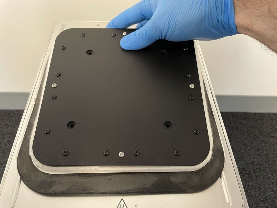 Mano con guante presionando una segunda esquina de la plataforma Fuse 1 hacia la cámara — repitiendo el proceso de asentamiento esquina por esquina