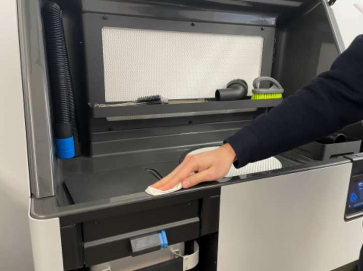 Mano limpiando el labio frontal de la superficie de trabajo del Fuse Sift con un paño limpio antes de la instalación de la junta