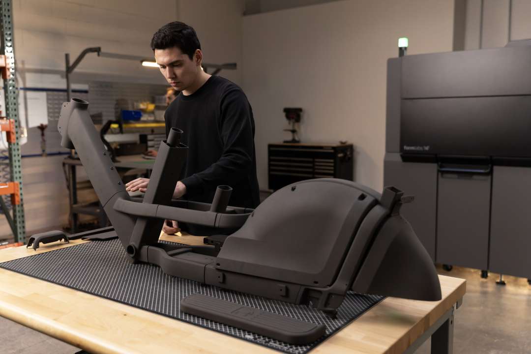 Técnico a montar grandes componentes mate escuros impressos em 3D com a Formlabs Fuse X1 sobre uma mesa de montagem