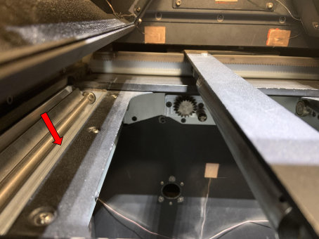 Flecha roja señalando el borde interior de la bandeja de polvo izquierda del Fuse 1 — zona crítica de acumulación de Nylon 12 GF