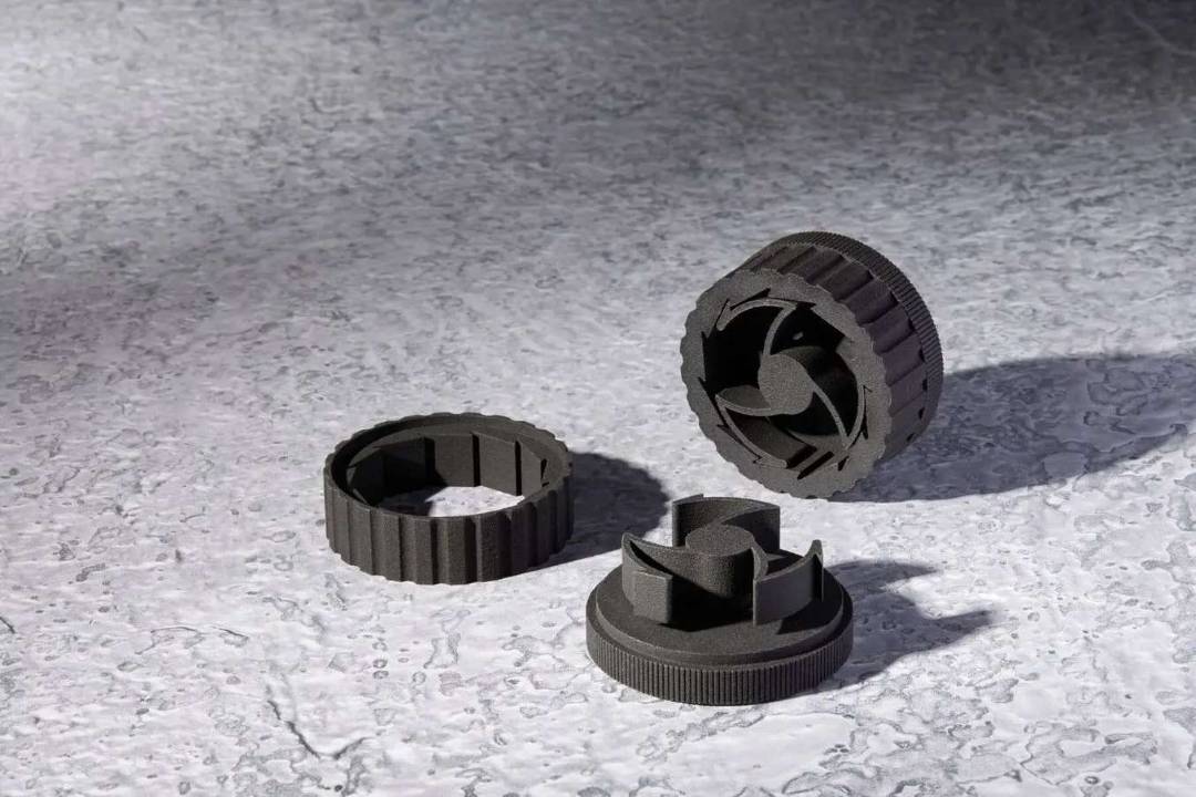 Tres componentes mecánicos de anillo dentado impresos en SLS con Nylon 12 Tough en gris oscuro — geometría interna compleja y acabado superficial detallado