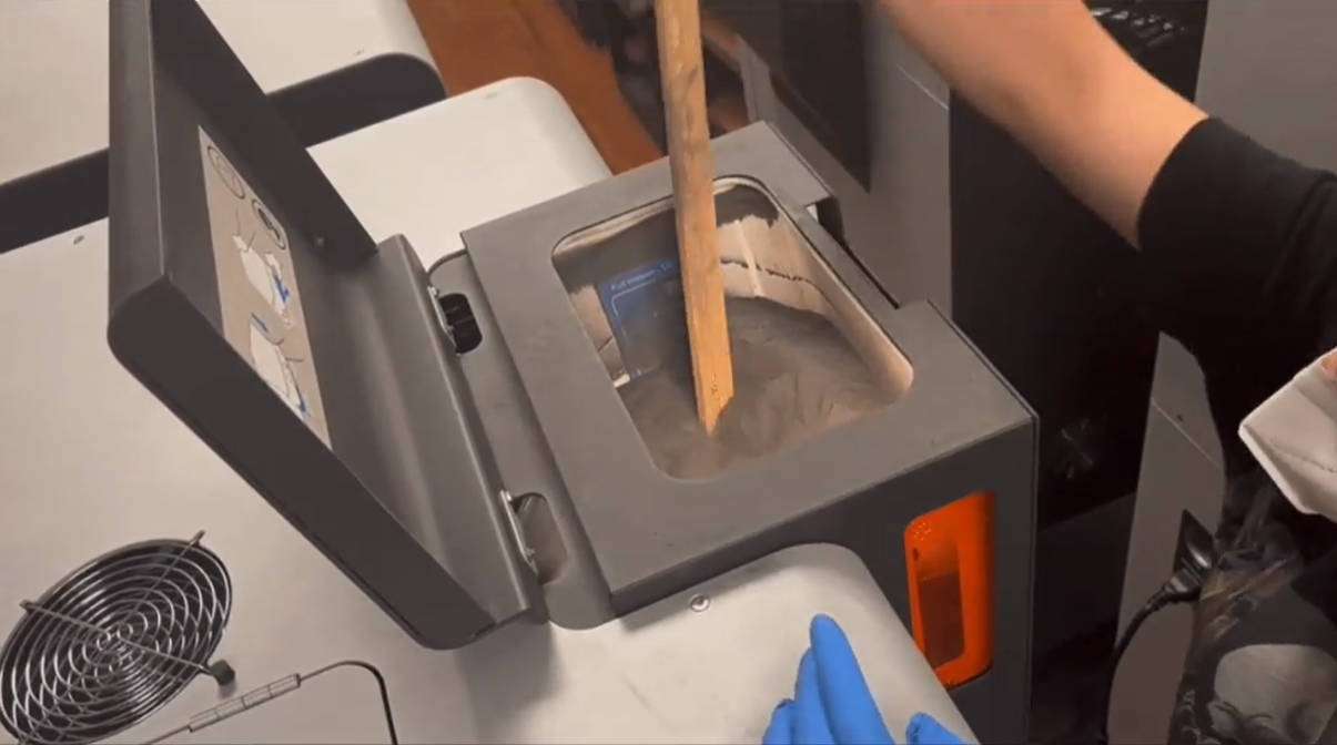 Removiendo polvo TPU 90A en la tolva del Fuse Sift con una varilla de madera para garantizar el flujo adecuado antes de la impresión