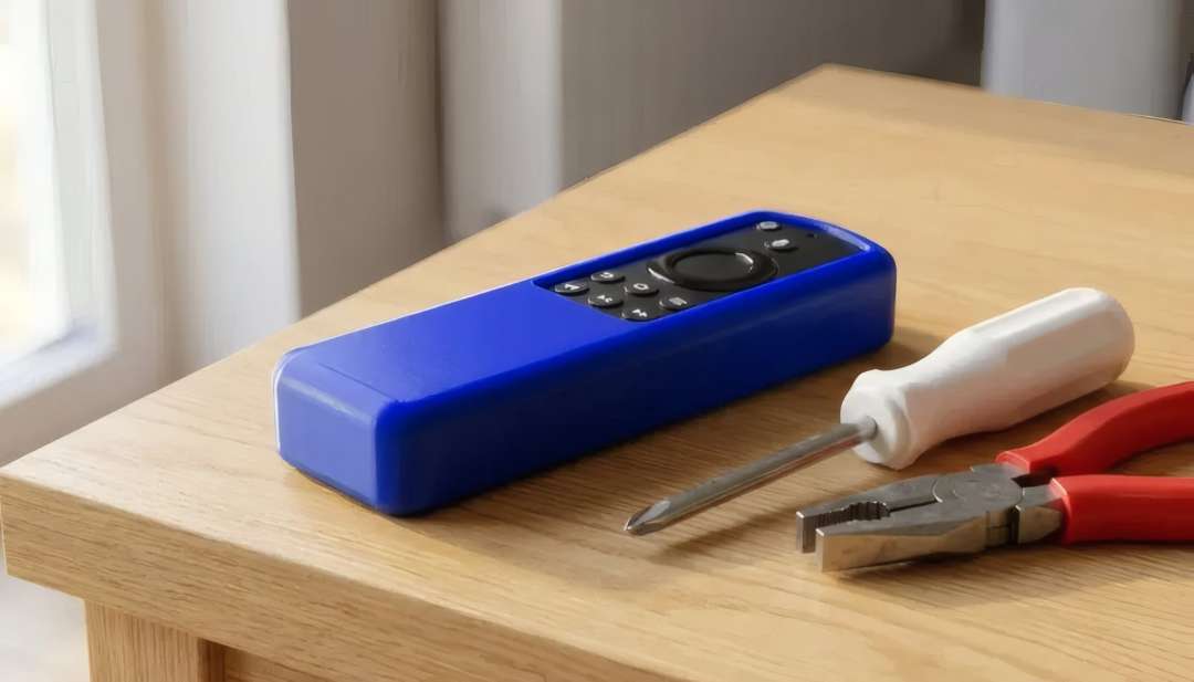 Una carcasa rectangular azul con botones negros descansa sobre una mesa de madera cerca de un destornillador y unos alicates.