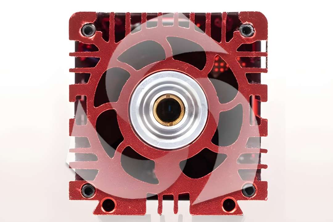 Front-face close-up of Ortur LU2-4-SF laser module showing large radial cooling fan blades and central brass lens aperture in red anodized heatsink
