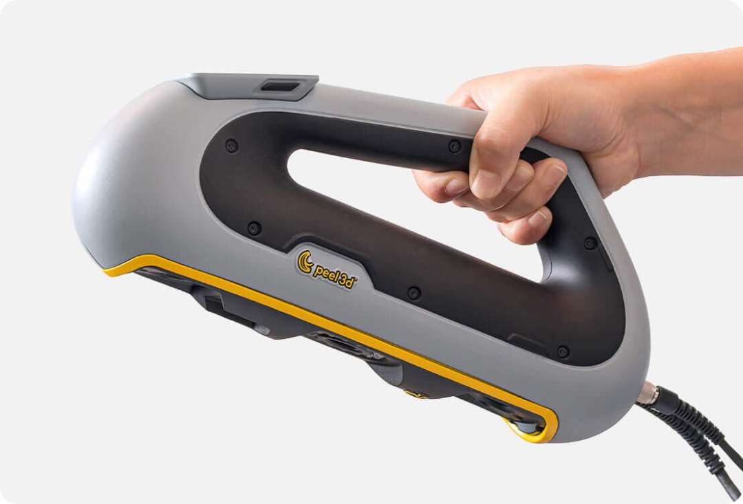 Mano sosteniendo el escáner 3D portátil gris y amarillo Peel 3 por su empuñadura ergonómica