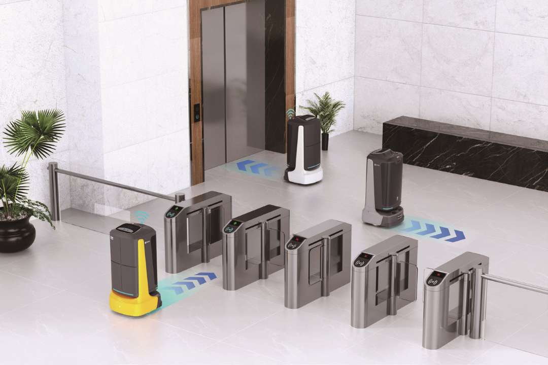 PUDU FlashBot y otros robots PUDU navegando a través de torniquetes de barrera abatible de acero inoxidable en un vestíbulo de oficinas de mármol con un ascensor visible al fondo