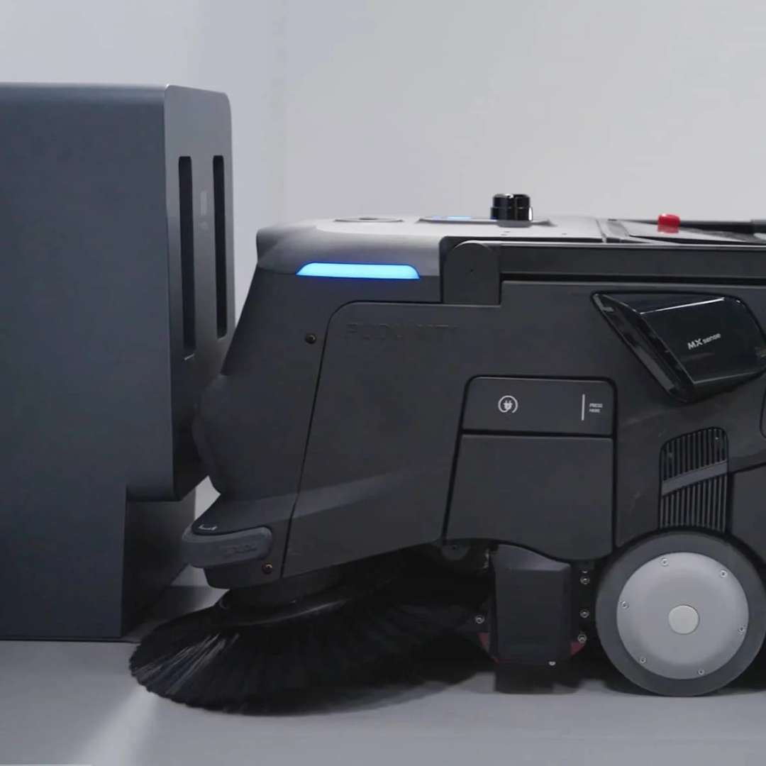 Robot de limpieza autónomo PUDU MT1 Vac acoplado en su base de carga con LED azul activo, mostrando el posicionamiento automático de retorno a carga
