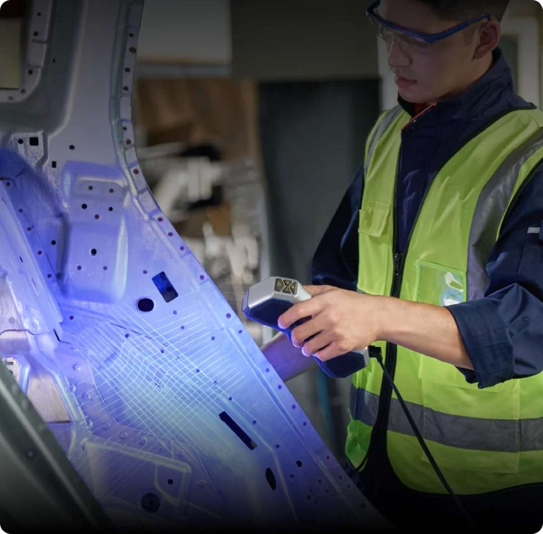 Un técnico escanea el panel de la carrocería de un coche con un escáner 3D portátil que proyecta luz estructurada azul, con una malla superpuesta