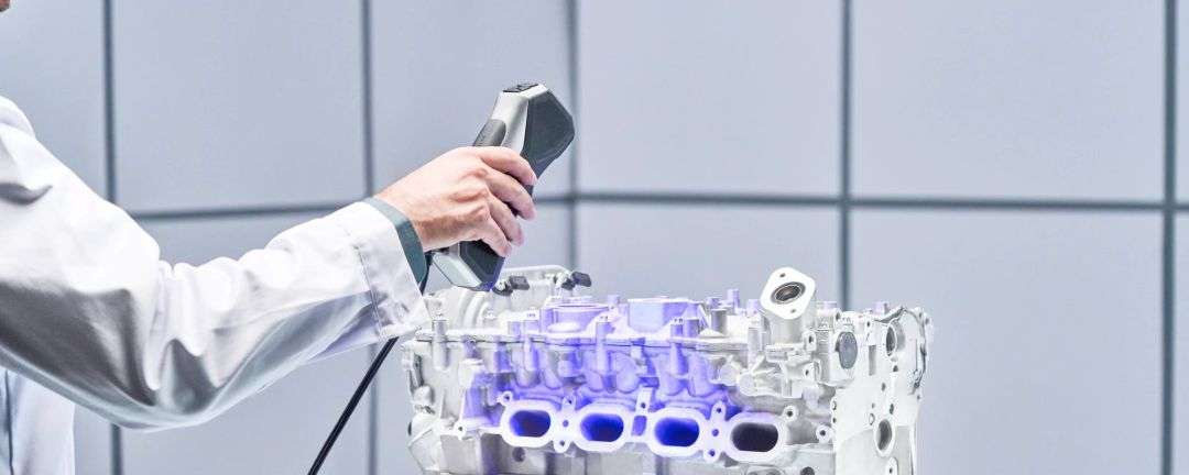 El escáner 3D portátil captura la culata del bloque de cilindros de un motor con proyección de luz estructurada azul sobre la superficie