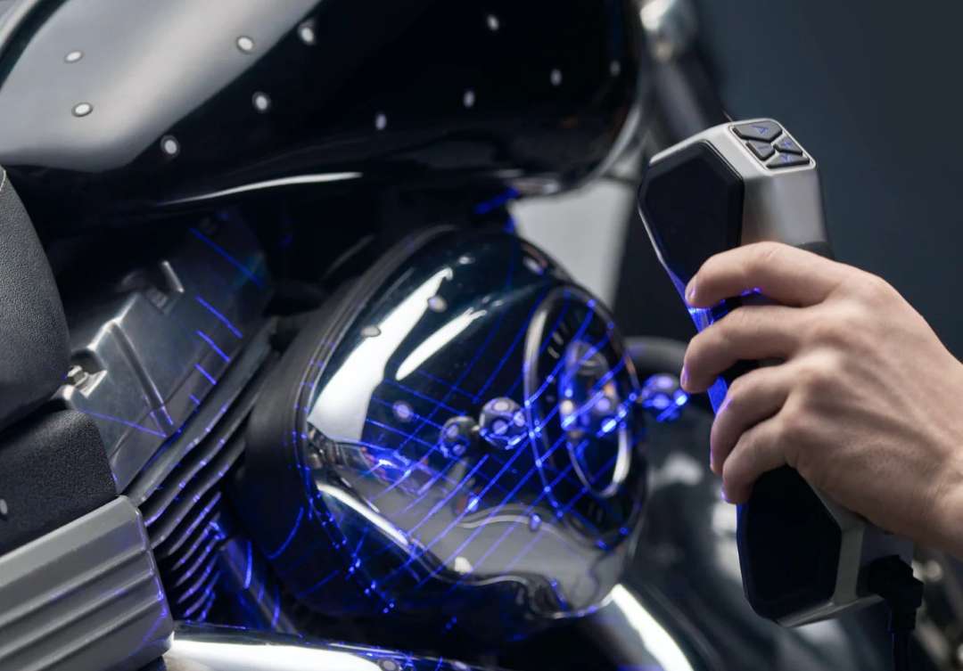 El escáner portátil proyecta líneas láser azules en forma de malla sobre la superficie negra y brillante del motor de una motocicleta