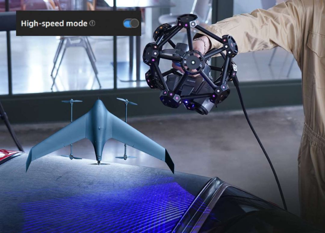 Escáner TE25 del FreeScan Trak Pro2 en modo de alta velocidad proyectando 50 líneas láser azules sobre la superficie de un vehículo, con un modelo 3D de un dron visible de fondo