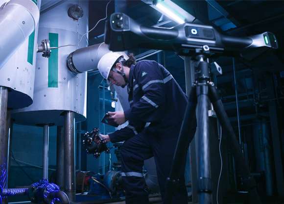 Ingeniero utilizando el escáner portátil FreeScan UE Nova para medir tuberías y válvulas industriales en un entorno de fábrica sin marcadores