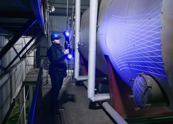 FreeScan UE Nova inalámbrico proyectando líneas láser azules sobre un gran recipiente de presión industrial durante el escaneo