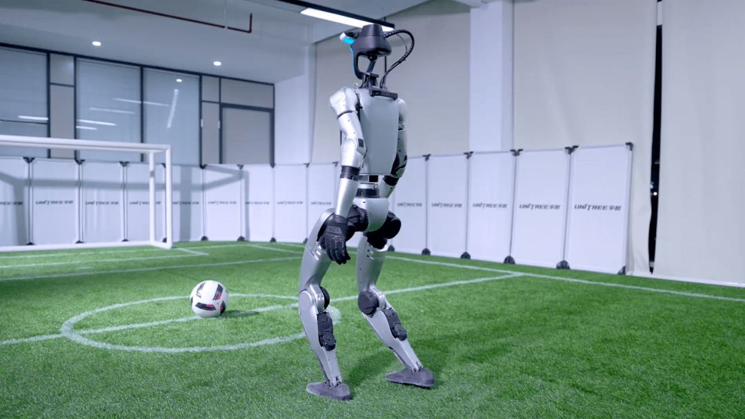 Robot humanoide Unitree G1-Comp EDU aproximándose a un balón de fútbol en una pista de pruebas interior durante la validación de política de aprendizaje por refuerzo