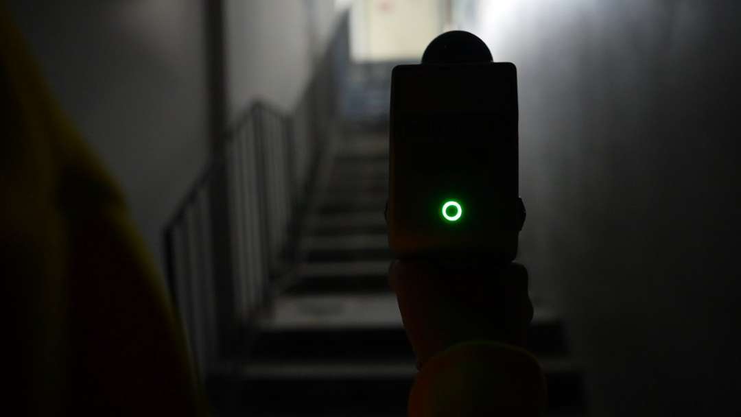 Escáner visto desde atrás: carcasa con el indicador iluminado en una caja de escaleras con poca luz